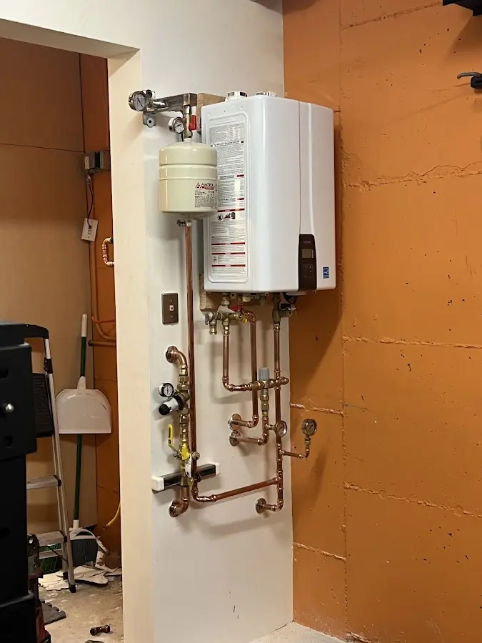 Plumbing technician inspecting water heater connections in Red Wing